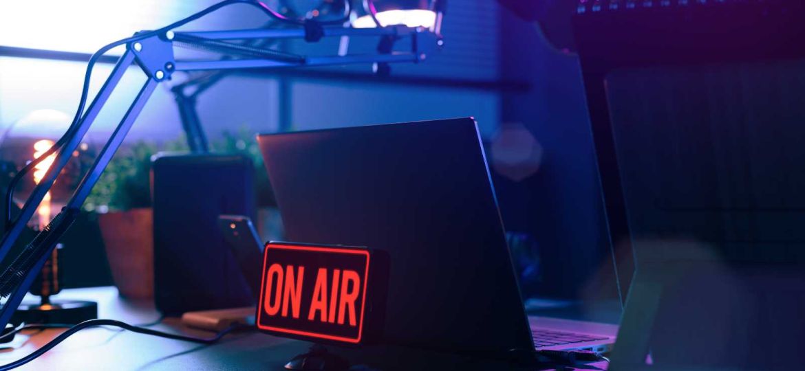 TV broadcasting on air sign in front of laptop on desk